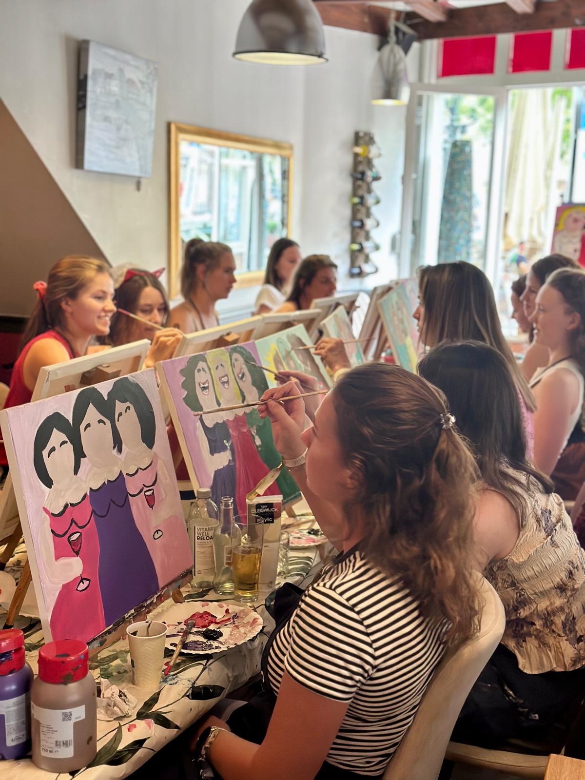 Deelnemers schilderen Picasso-portretten aan een lange tafel in een café